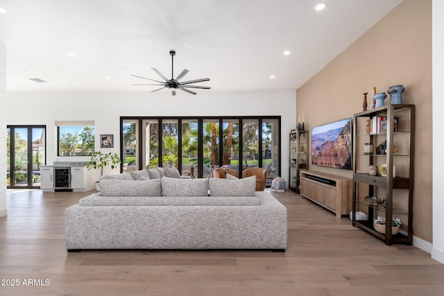 living room featuring wine cooler, ceiling fan, a healthy amount of sunlight, and light wood-type flooring