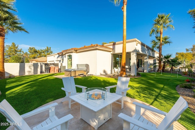 back of property featuring a yard, a patio, and a hot tub