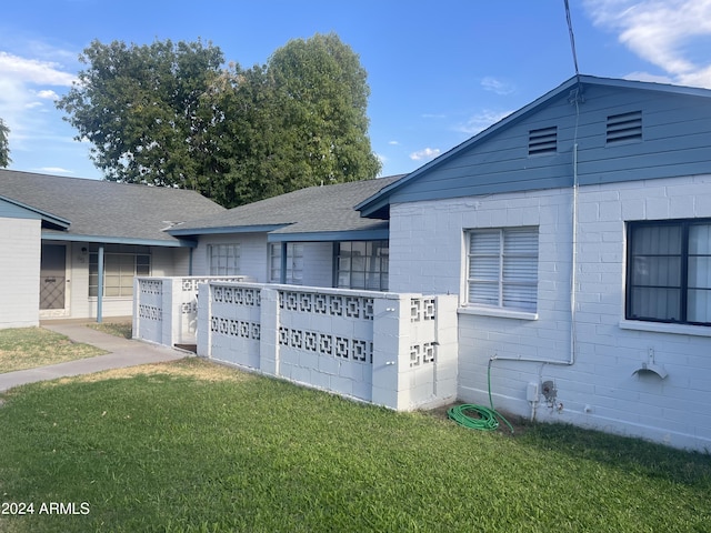view of home's exterior featuring roof with shingles and a yard