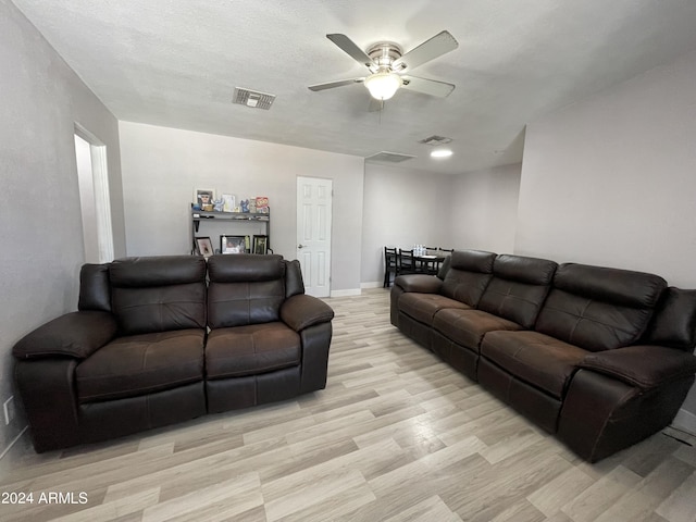 living area featuring a ceiling fan, visible vents, light wood-style floors, and baseboards