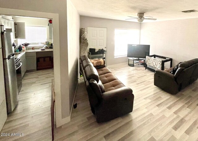 living room featuring a textured ceiling, light hardwood / wood-style floors, and ceiling fan