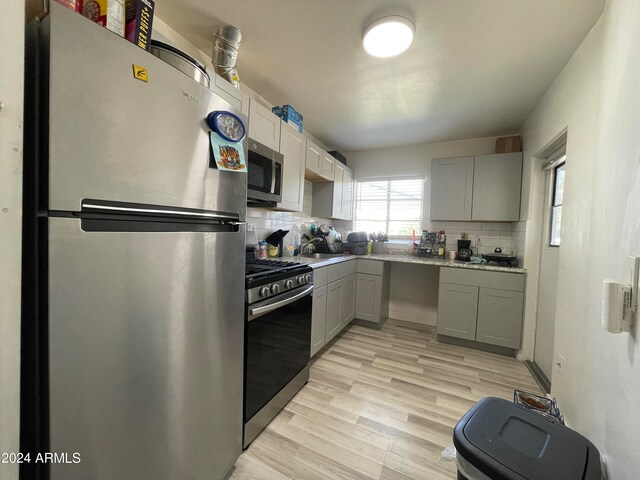 kitchen featuring tasteful backsplash, gray cabinets, stainless steel appliances, and light countertops