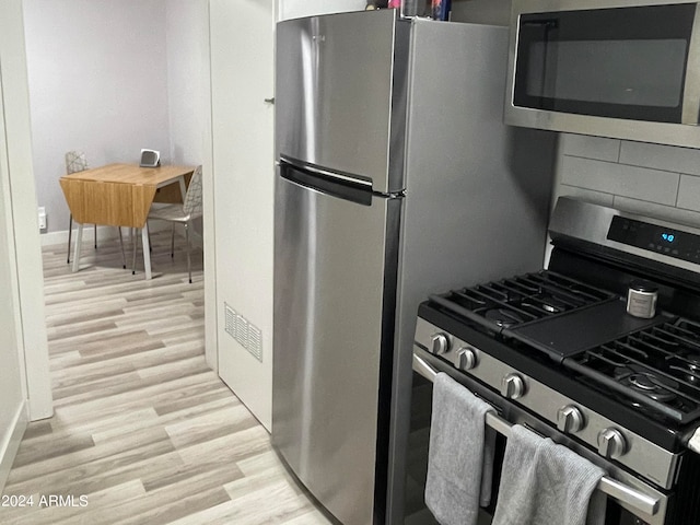 kitchen featuring stainless steel appliances, light wood-style flooring, and baseboards