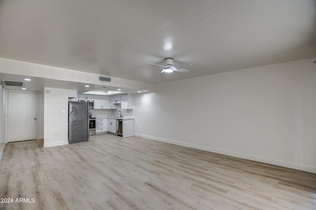 unfurnished living room featuring ceiling fan, sink, and light hardwood / wood-style floors