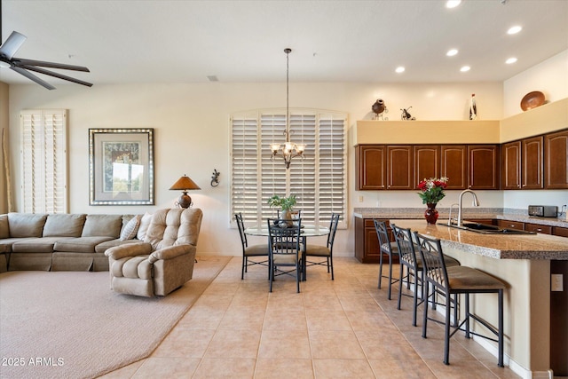 kitchen featuring open floor plan, dark brown cabinets, decorative light fixtures, and a kitchen breakfast bar