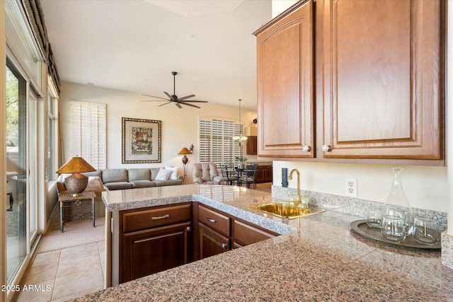 kitchen with tile counters, open floor plan, light tile patterned flooring, a sink, and a peninsula