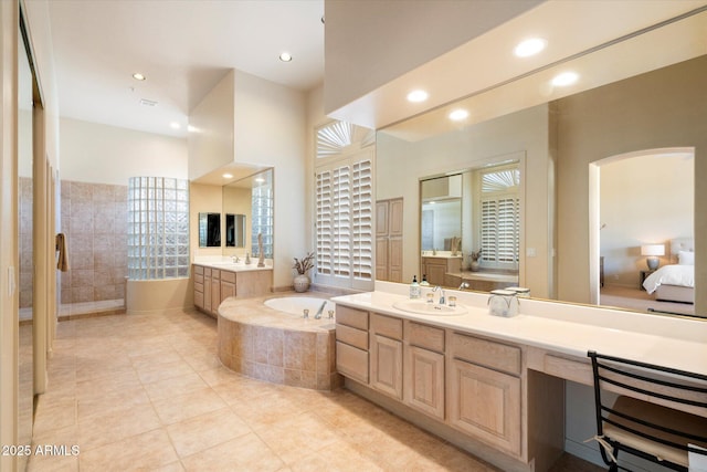 ensuite bathroom featuring tile patterned flooring, two vanities, a sink, and a walk in shower