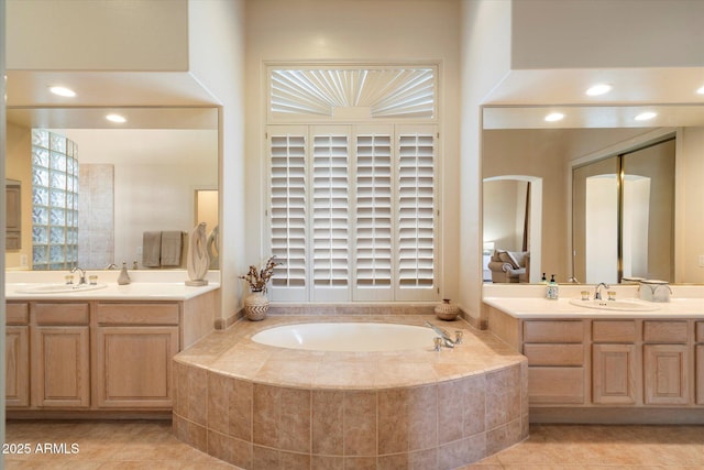 bathroom with a garden tub, two vanities, tile patterned flooring, and a sink