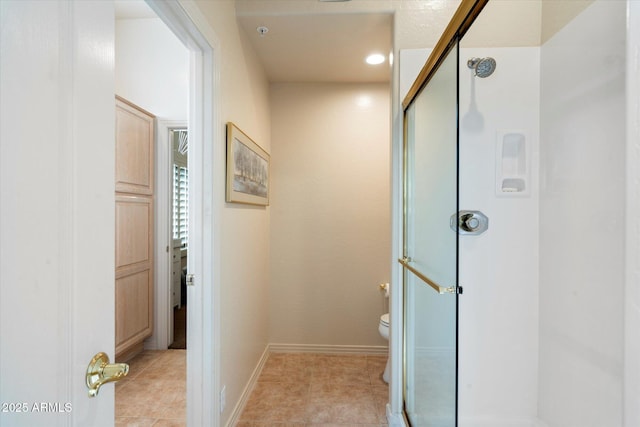 bathroom featuring toilet, a stall shower, tile patterned flooring, and baseboards