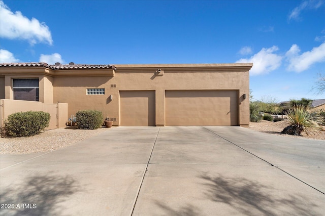 view of front of home with an attached garage, driveway, a tiled roof, and stucco siding