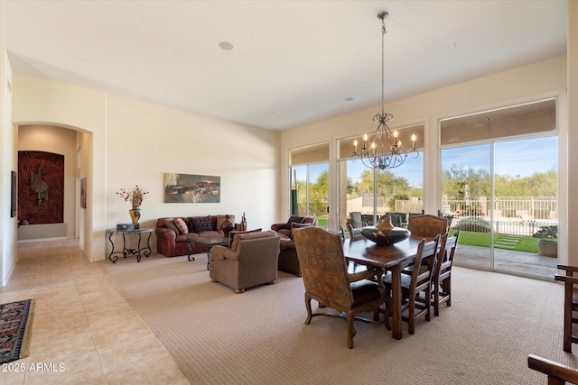 dining area with arched walkways, light tile patterned flooring, plenty of natural light, and an inviting chandelier