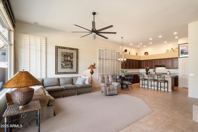 living area featuring ceiling fan with notable chandelier, recessed lighting, and light tile patterned floors