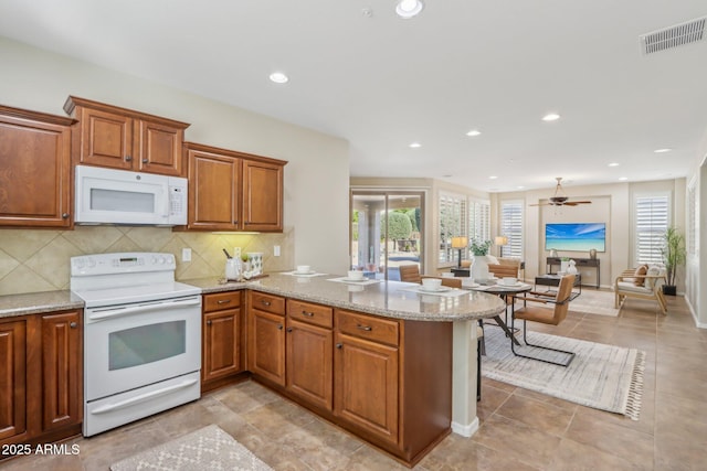 kitchen with tasteful backsplash, white appliances, plenty of natural light, and kitchen peninsula