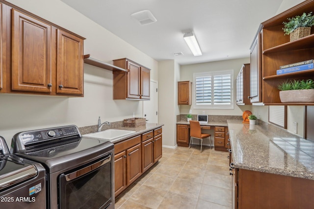 clothes washing area featuring sink, light tile patterned floors, washer and clothes dryer, and cabinets