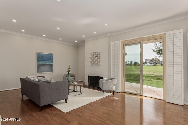 living room with a large fireplace, hardwood / wood-style floors, and crown molding