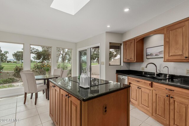 kitchen with dark stone countertops, dishwasher, a center island, a skylight, and sink