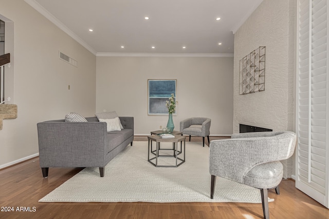 living room featuring ornamental molding, a large fireplace, and light hardwood / wood-style flooring