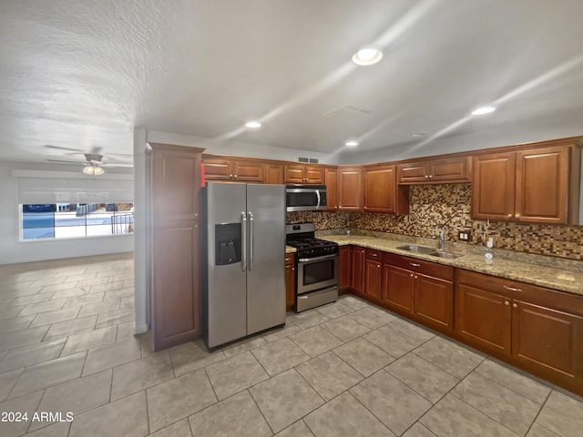 kitchen featuring stainless steel appliances, ceiling fan, light tile patterned flooring, sink, and light stone counters