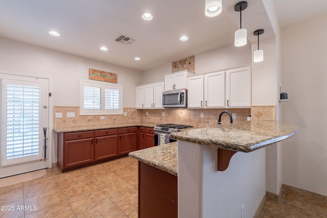 1927 W Mine Trl, Phoenix, AZ 85085 - kitchen featuring appliances with stainless steel finishes, a peninsula, light stone counters, white cabinetry, and tasteful backsplash
