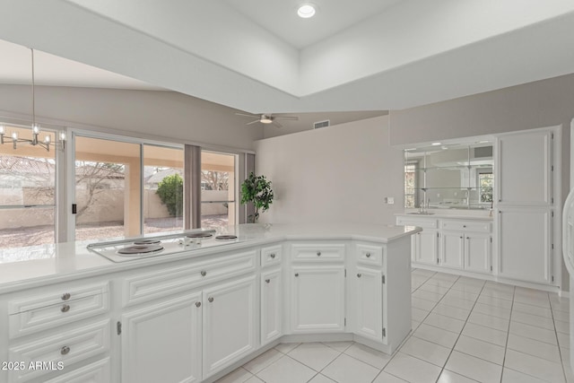 kitchen featuring light tile patterned floors, white stovetop, white cabinets, kitchen peninsula, and pendant lighting