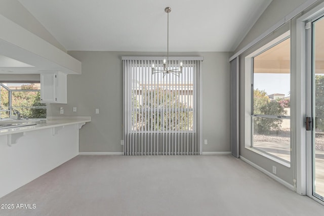 unfurnished dining area with plenty of natural light, light carpet, and vaulted ceiling