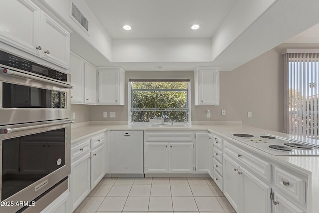 kitchen with white cabinets, white appliances, sink, and light tile patterned flooring