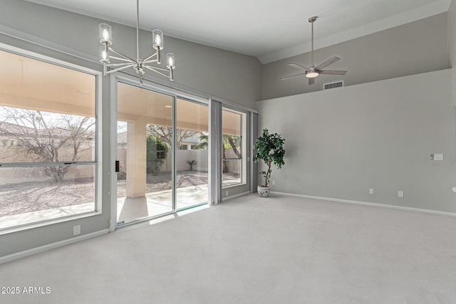 carpeted spare room with ceiling fan with notable chandelier and vaulted ceiling