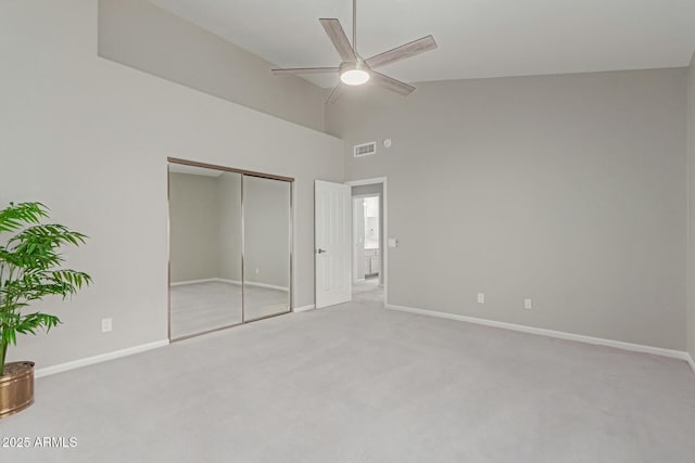 unfurnished bedroom with ceiling fan, light colored carpet, a closet, and high vaulted ceiling