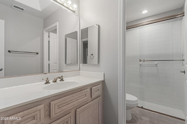 bathroom featuring vanity, toilet, and a shower with shower door