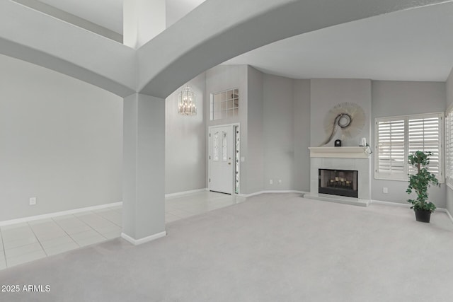 unfurnished living room featuring light tile patterned floors, a notable chandelier, and a tiled fireplace