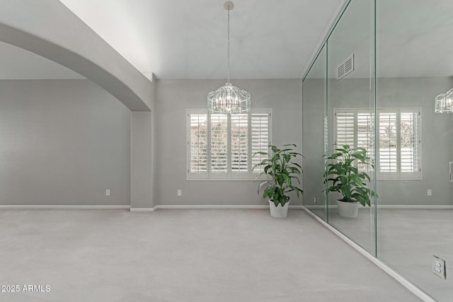 interior space with a chandelier, a wealth of natural light, and carpet floors