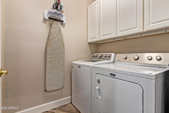 laundry room with cabinets, wood-type flooring, and washer and dryer