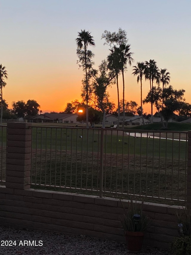 gate at dusk featuring a lawn