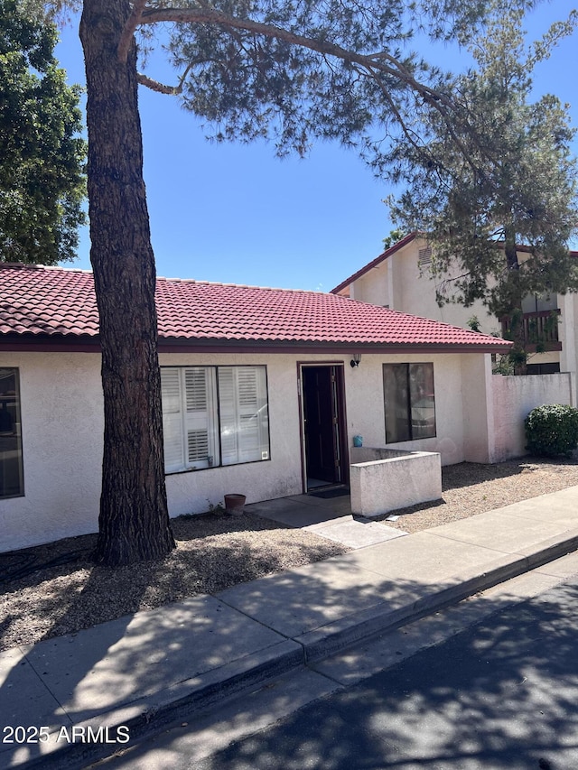 view of front of house featuring a tiled roof, fence, and stucco siding