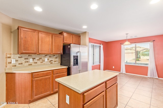 kitchen with stainless steel fridge, tasteful backsplash, light tile patterned floors, pendant lighting, and a center island