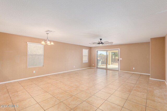 tiled empty room with a textured ceiling and ceiling fan with notable chandelier