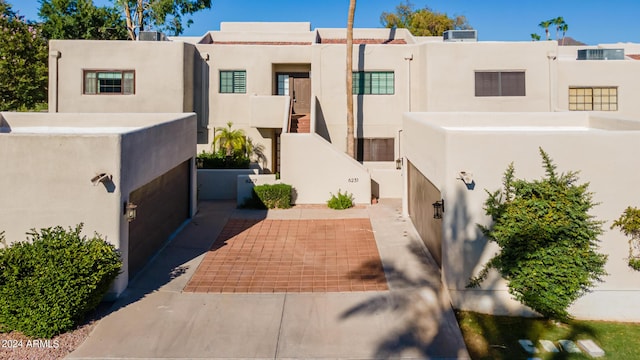 pueblo-style house with cooling unit and stucco siding