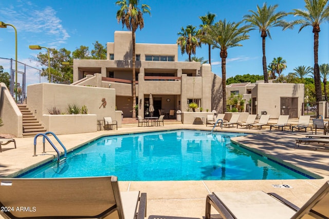 community pool featuring stairs, fence, and a patio