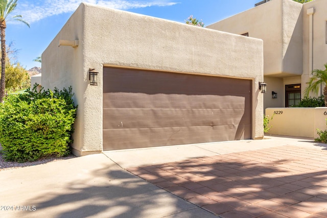 view of front facade with a garage, driveway, and stucco siding