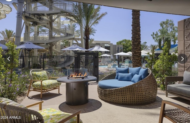 view of patio / terrace featuring an outdoor fire pit, fence, a balcony, and a community pool