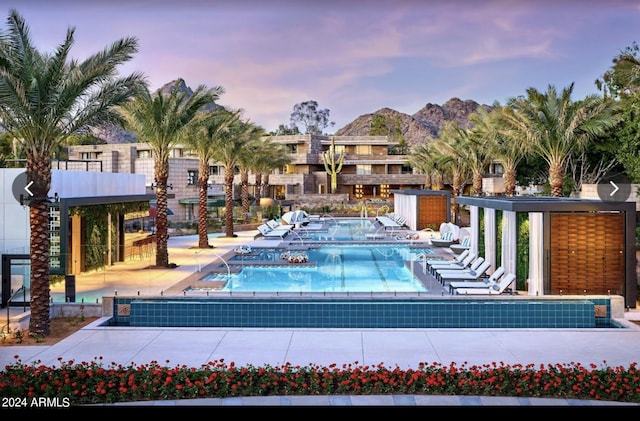 pool at dusk featuring a patio area, a community pool, and a mountain view