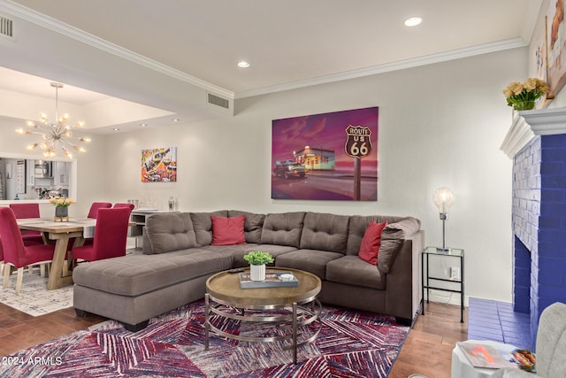 living room with a fireplace, a notable chandelier, visible vents, ornamental molding, and wood finished floors