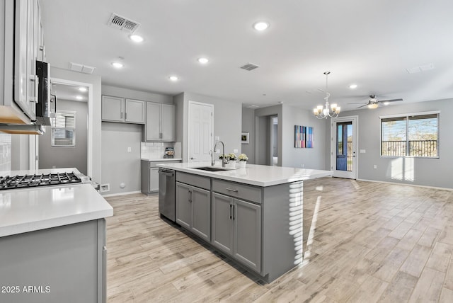 kitchen featuring decorative light fixtures, tasteful backsplash, a kitchen island with sink, gray cabinets, and sink