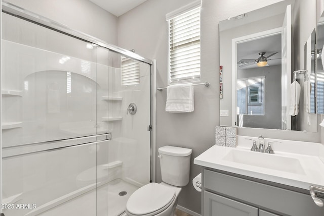 bathroom featuring ceiling fan, a shower with door, vanity, and toilet