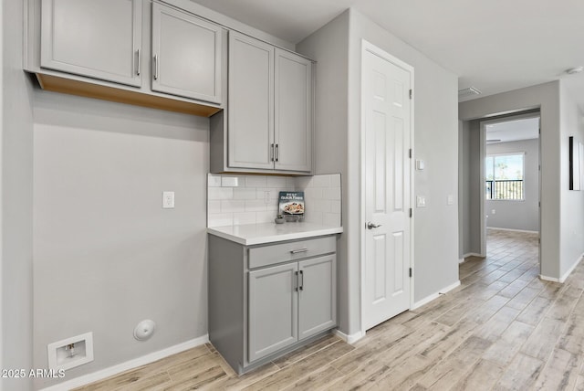 kitchen featuring light hardwood / wood-style floors, tasteful backsplash, and gray cabinets