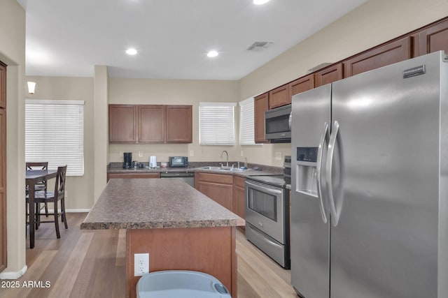 2118 N 77th Ln, Phoenix, AZ 85035 - kitchen featuring stainless steel appliances, a sink, light wood-style flooring, a center island, and recessed lighting