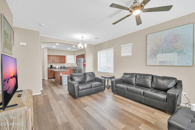 2118 N 77th Ln, Phoenix, AZ 85035 - living room featuring a chandelier, light wood finished floors, a ceiling fan, baseboards, and arched walkways