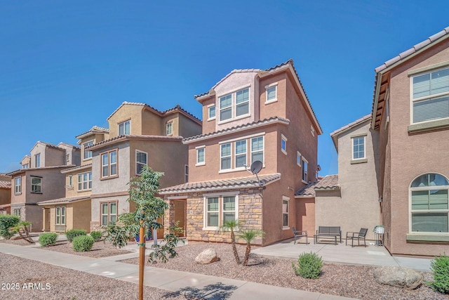 2118 N 77th Ln, Phoenix, AZ 85035 - view of front of property with a tiled roof, stucco siding, a patio area, stone siding, and a residential view