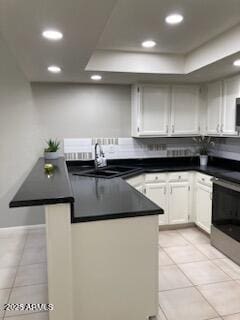 kitchen with sink, white cabinetry, range, light tile patterned floors, and kitchen peninsula