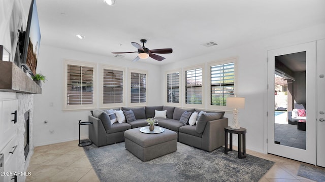 living area with visible vents, baseboards, ceiling fan, a fireplace, and light tile patterned flooring